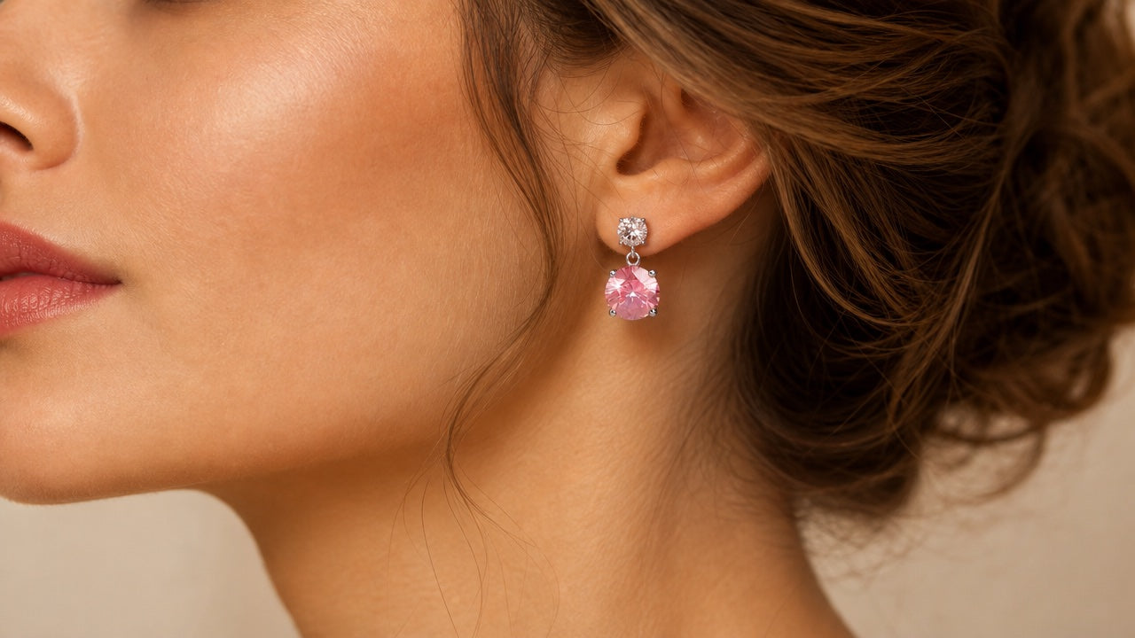 Pink crystal drop earring worn on an ear, from a 7-pair set