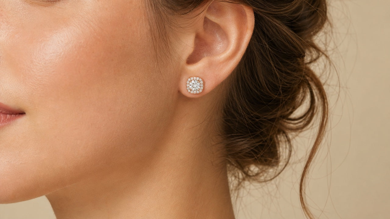 Rose gold cushion-halo stud earring worn on an ear